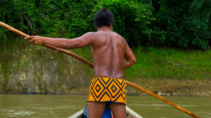 Homem indígena navega através de canoa em rio no Brasil