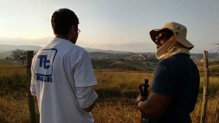 Dois profissionais da Tetra Tech conversando à frente de uma paisagem com morros e cidade.