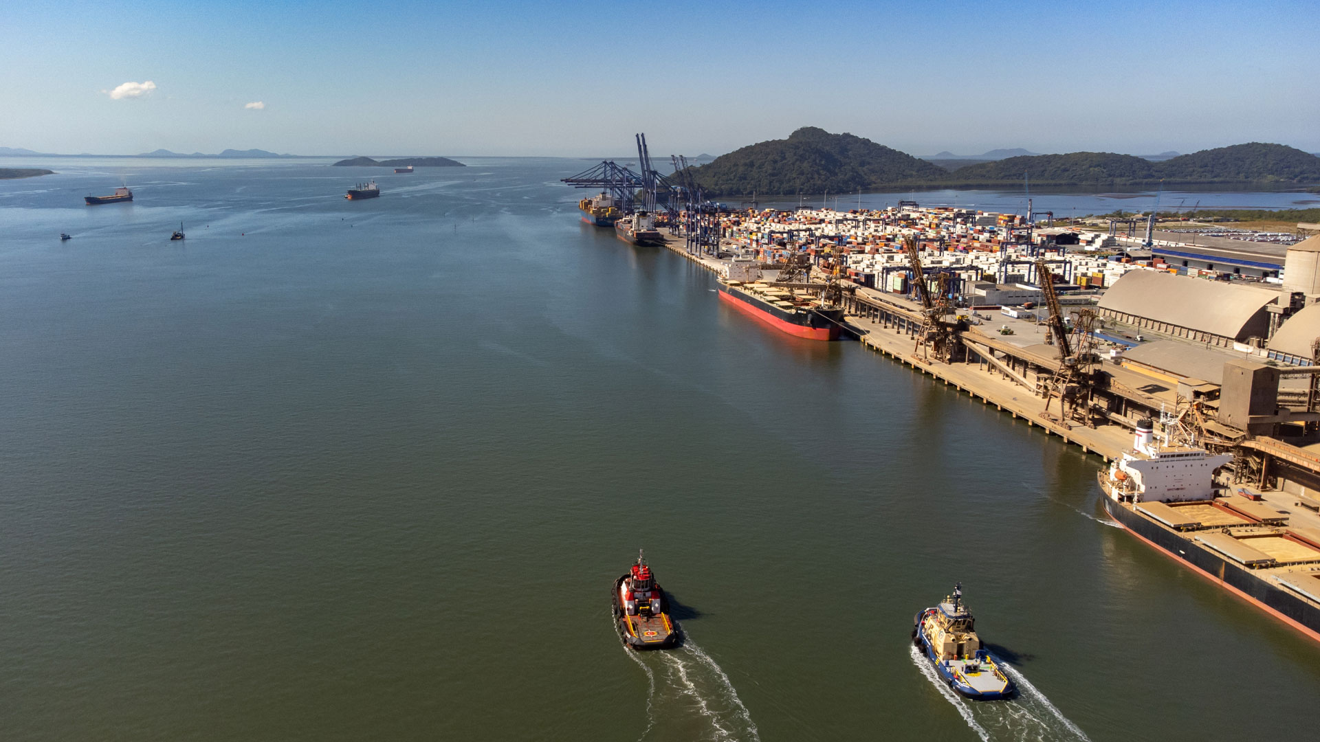 Botes trafegam ao lado de grande porto.