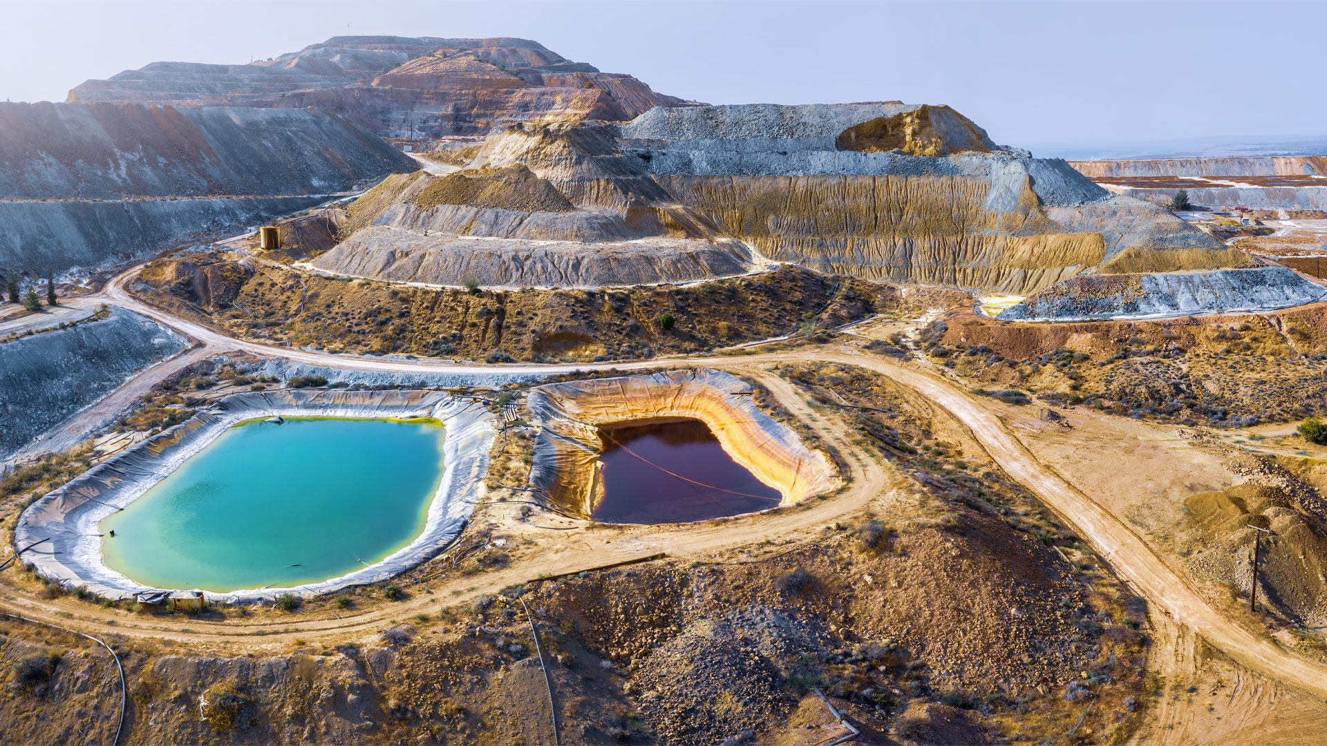 Panorama aéreo da mina de cobre, com pilhas de minério e piscinas multicoloridas.